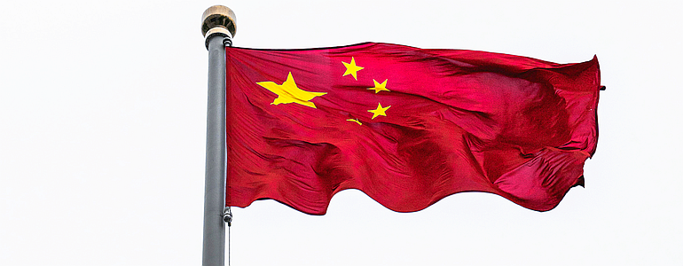 A Chinese flag flies on a high pole